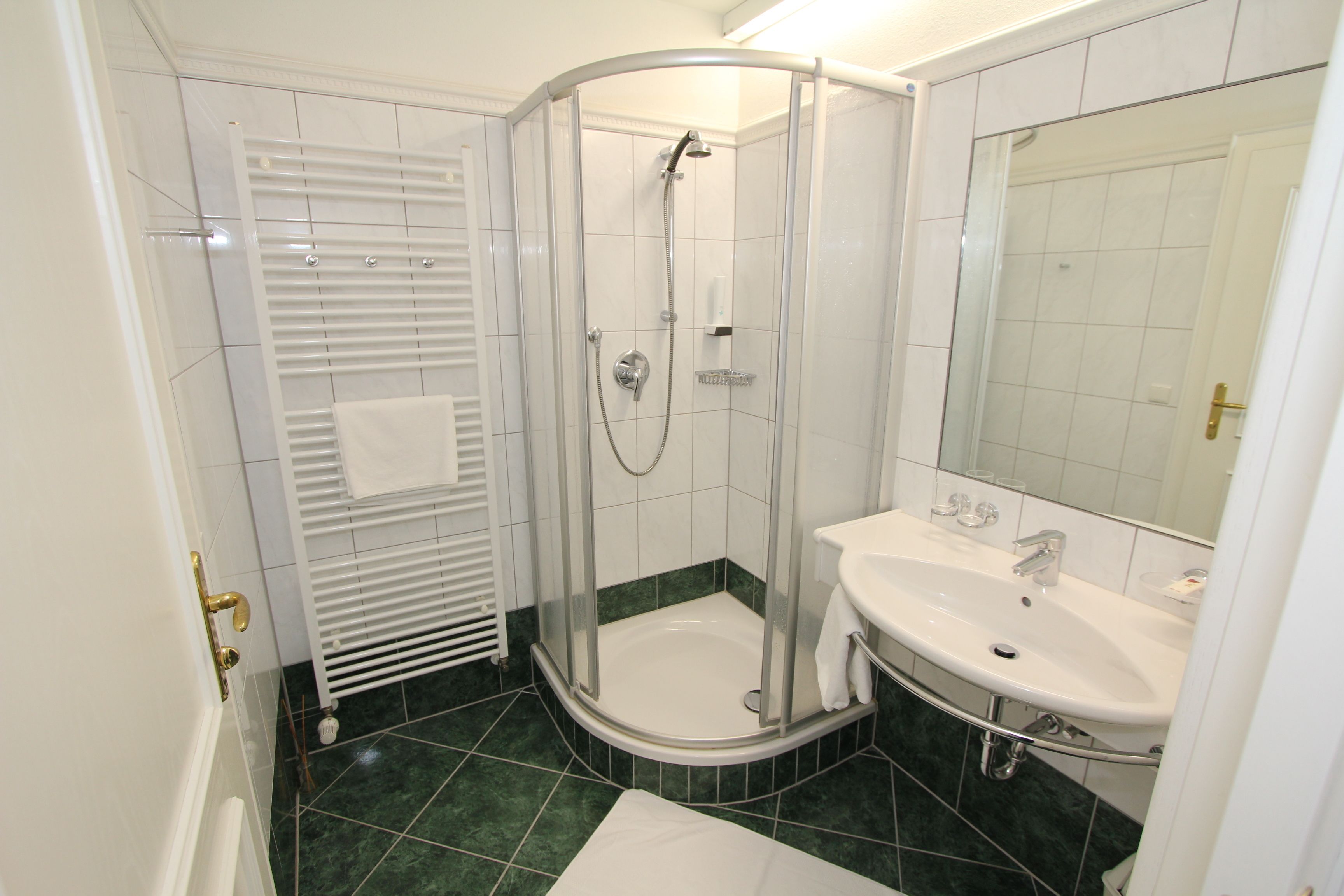 A modern bathroom with a glass-enclosed shower, a white sink, and a large mirror.