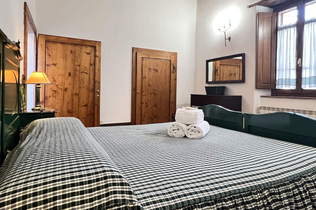 Een slaapkamer met een bed, houten deuren, een spiegel en een raam met gordijnen.