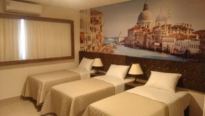 Une chambre d’hôtel avec deux lits, un grand tableau représentant Venise et un climatiseur fixé au mur.