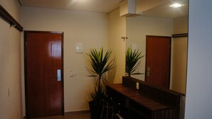 Un couloir avec une porte en bois, un comptoir d’accueil et deux plantes en pot.