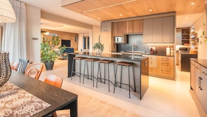 A modern kitchen with a central island, bar stools, and a dining area with a table and chairs. - 52 Victoria (Cape Town)