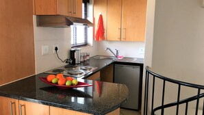 A kitchen with wooden cabinets, a stainless steel range hood, a sink, and a dishwashing machine. - 13 Eikehoff (Stellenbosch)