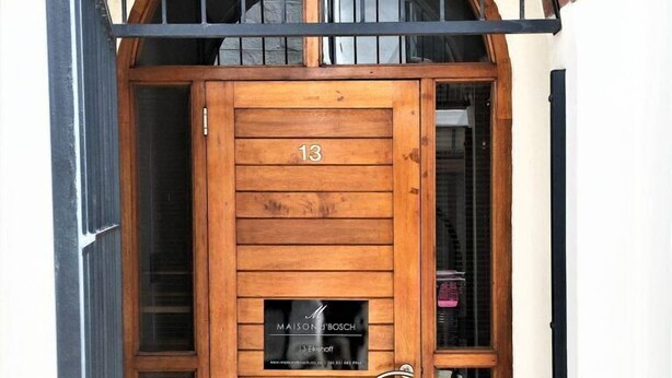 A wooden door with the number 13, a glass panel with the text "MAISON D'BOCH", and a metal gate above. - 13 Eikehoff (Stellenbosch)