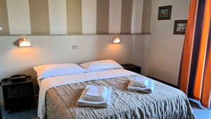 A hotel room with a bed, two bedside tables, and a nightstand with a phone. - Hotel Palace (Cesenatico)