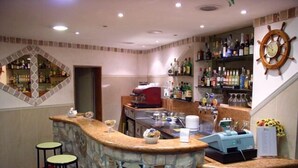 A bar area with a stone counter, stools, a coffee machine, and shelves with bottles. - Hotel Palace (Cesenatico)