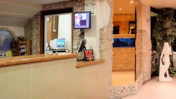 A reception area with a stone wall, a reception desk, a computer, and a television.