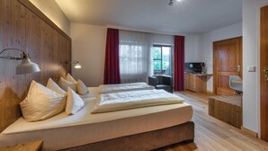 Ein Hotelzimmer mit einem großen Bett, einem Schreibtisch, einem Fernseher und einem Fenster mit Vorhängen.