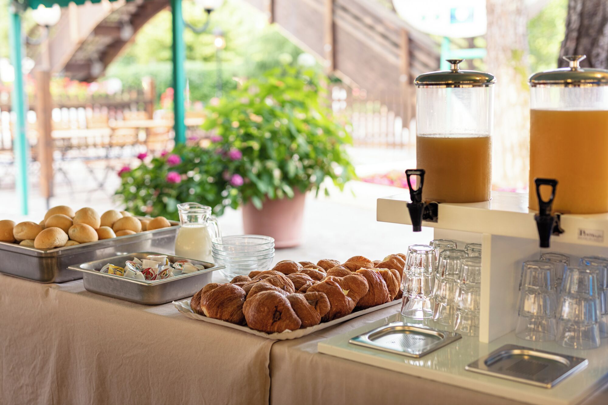 A breakfast buffet with pastries, bread, and beverages.