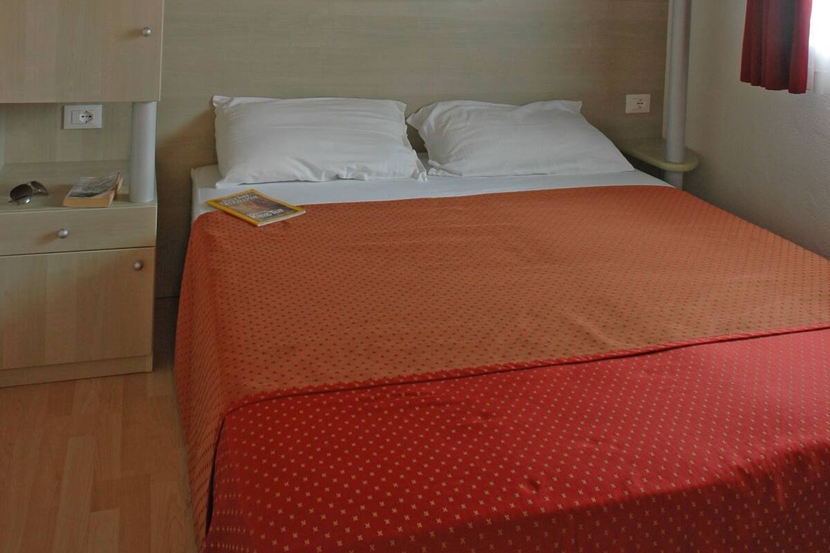 A bedroom with a bed, a wardrobe, and a shelf unit.