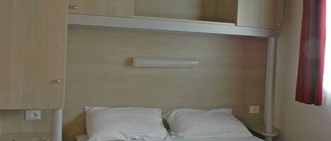 A bedroom with a bed, a wardrobe, and a shelf unit.