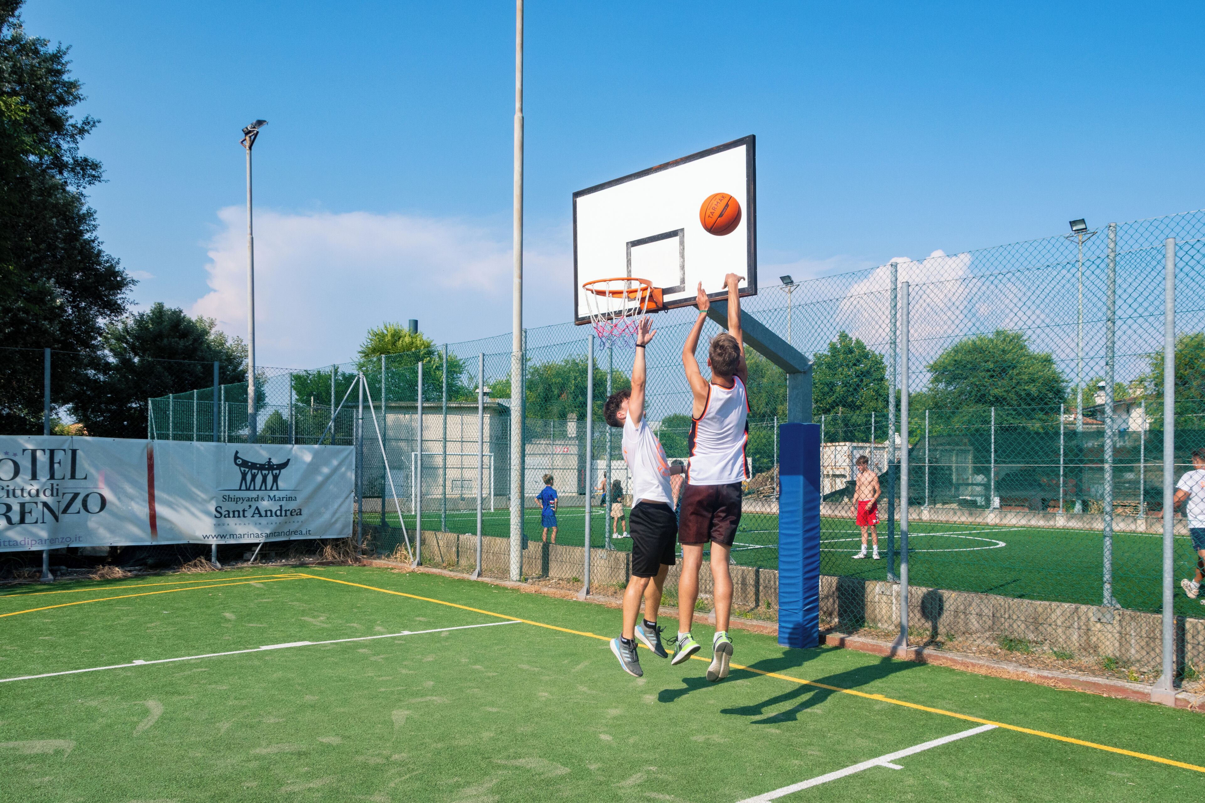 A basketball court with a net, a banner, and a fence.