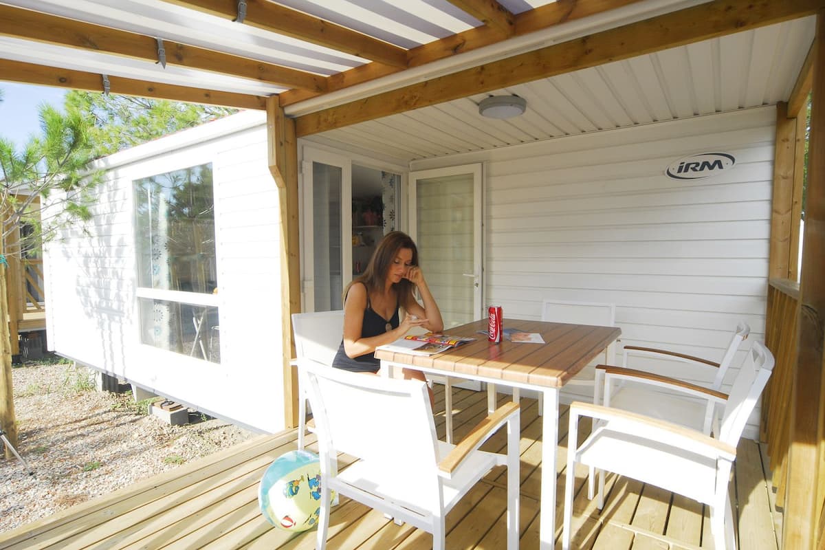 A covered outdoor area with a wooden table and chairs, a Coca-Cola can, and a volleyball.
