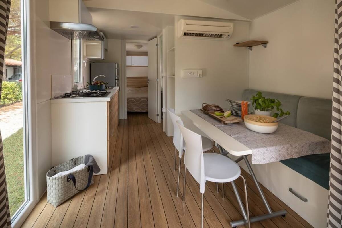 A compact kitchen with a stove, sink, and a dining area with a table and chairs.
