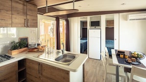 Una cocina compacta con armarios de madera, un lavamanos y una zona de comedor con mesa y sillas.