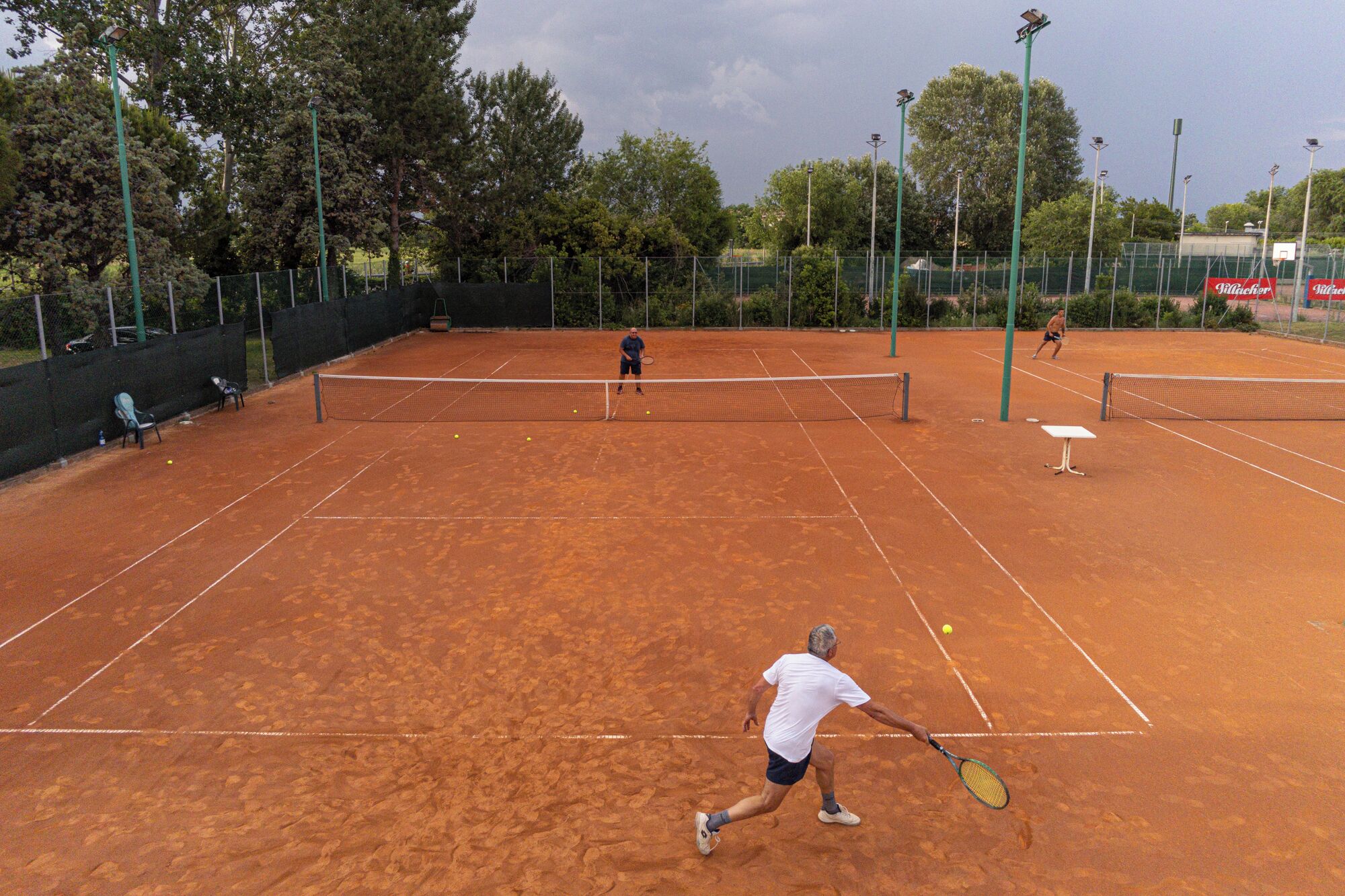 A tennis court with a net, two players, and a table tennis table.