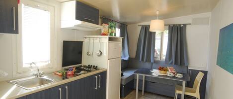 A compact kitchen with a gas stove, sink, and a small dining area with a table and chairs.