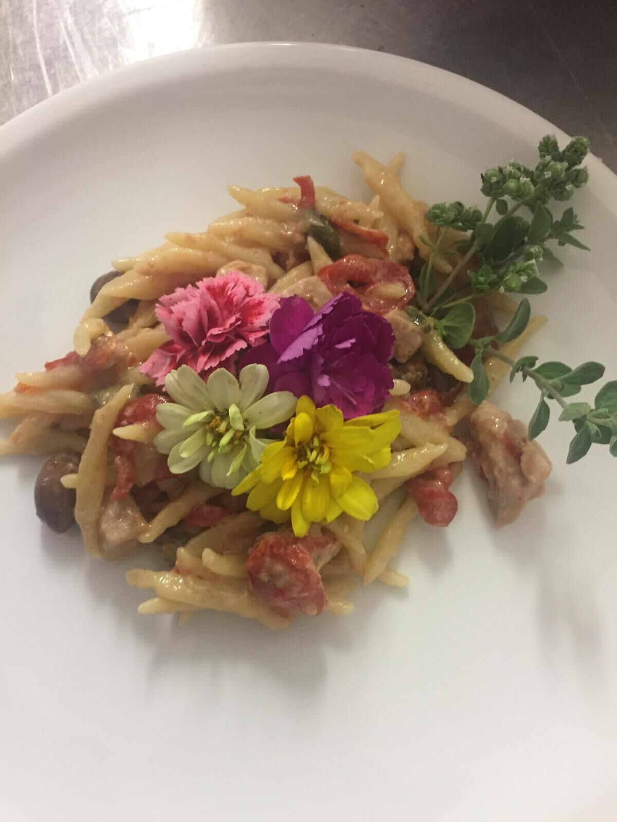 A plate of pasta with vegetables and flowers.