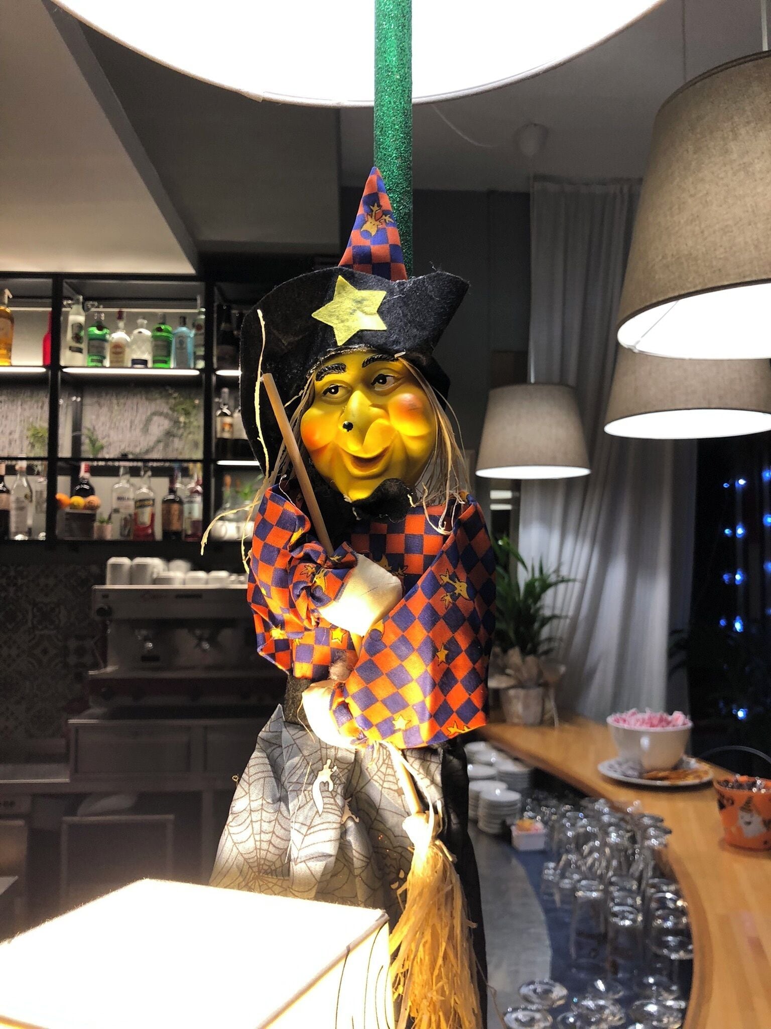 Un espace bar agrémenté d’une statue décorative, d’étagères remplies de bouteilles et d’un comptoir avec des verres.