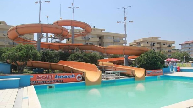 Una piscina con varias toboganes acuáticos y un letrero que dice 'Sun Beach Ristorante'.