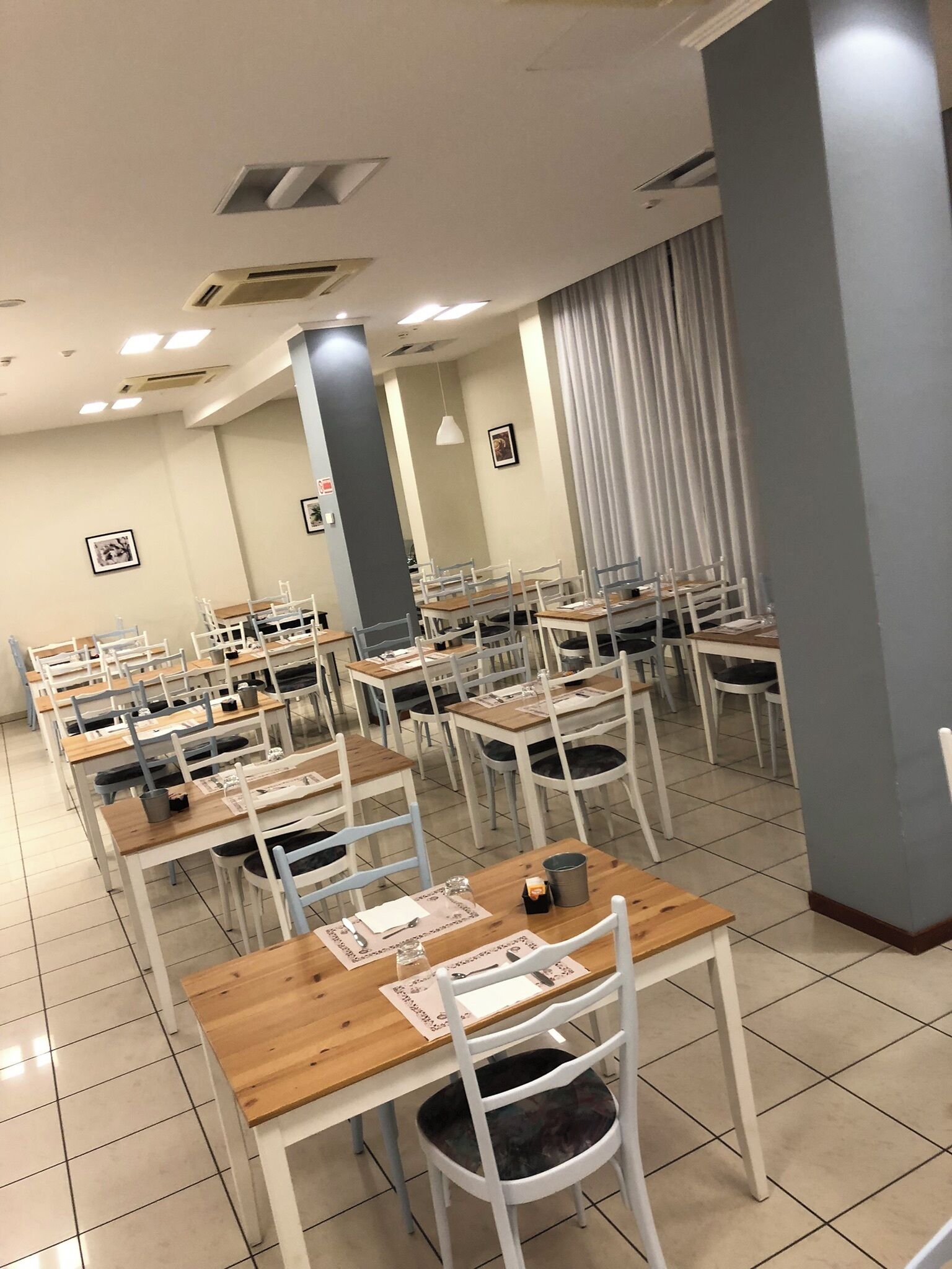 Un comedor con varias mesas y sillas, dispuestas en filas.
