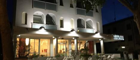 A two-story building with a balcony, large windows, and outdoor seating.
