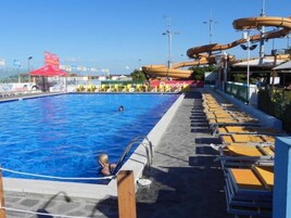 Una piscina con tobogán y sillas de descanso.