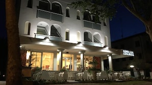 Un hotel de dos pisos con un balcón en el nivel superior, zona de estar al aire libre y un cartel que indica que es un hotel.