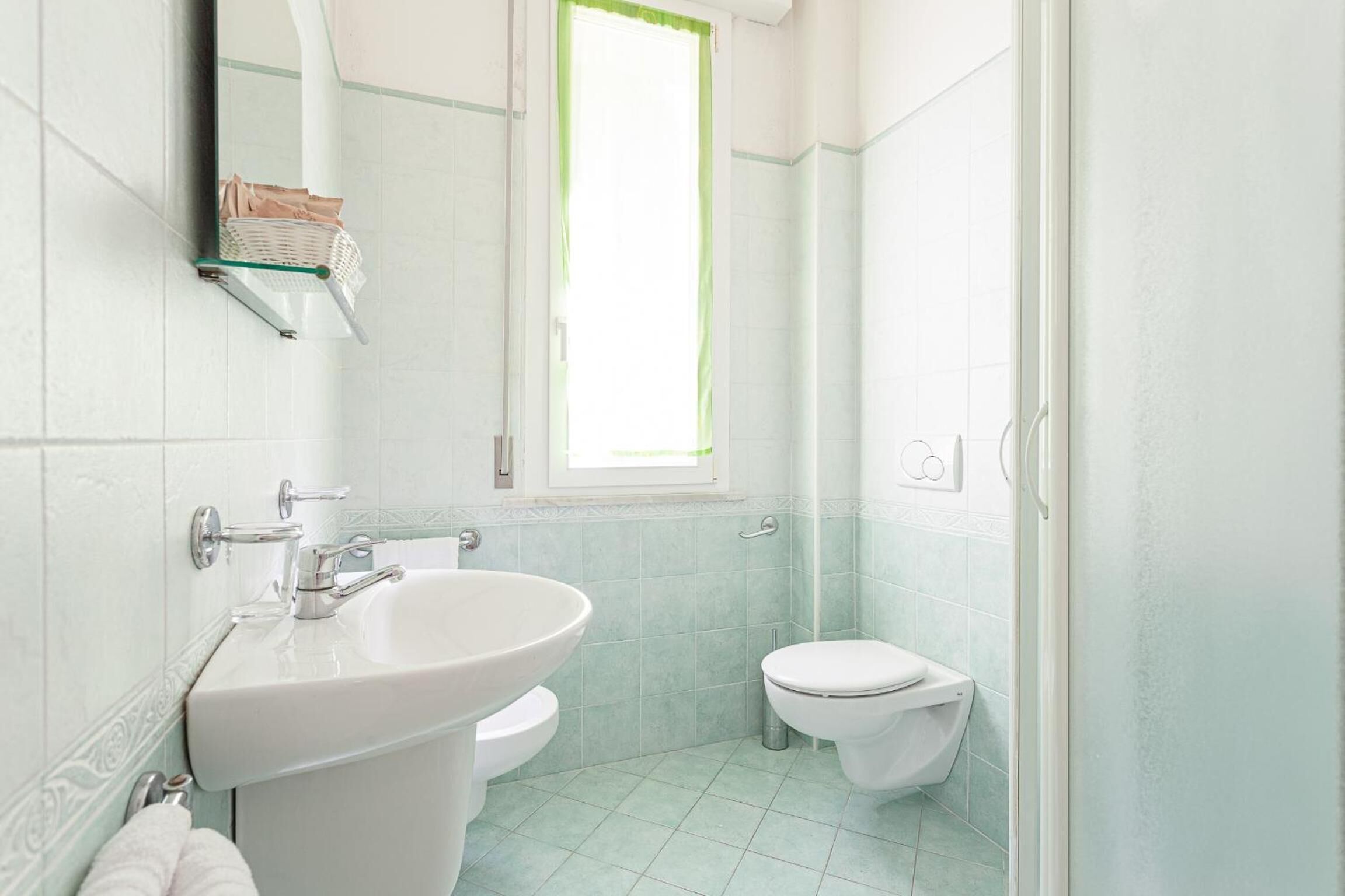 Een badkamer met een wastafel, toilet en een raam.