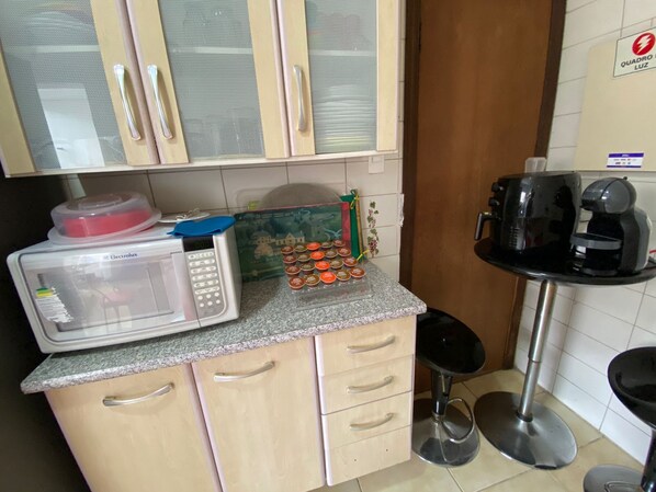 A kitchen with a microwave, a coffee maker, and a small refrigerator. - Acomodações Hamzo (São Paulo)