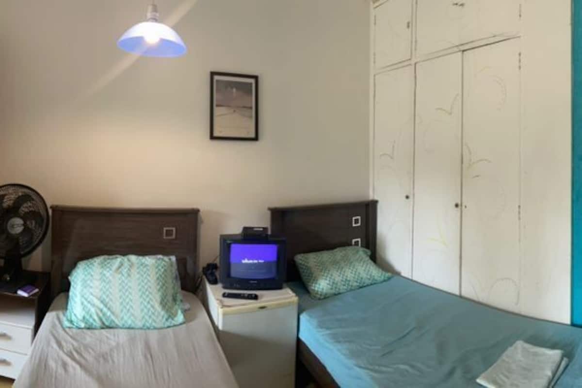 Une chambre avec des lits superposés, une armoire, un bureau avec un ordinateur et un lit recouvert d’une couverture bleue.