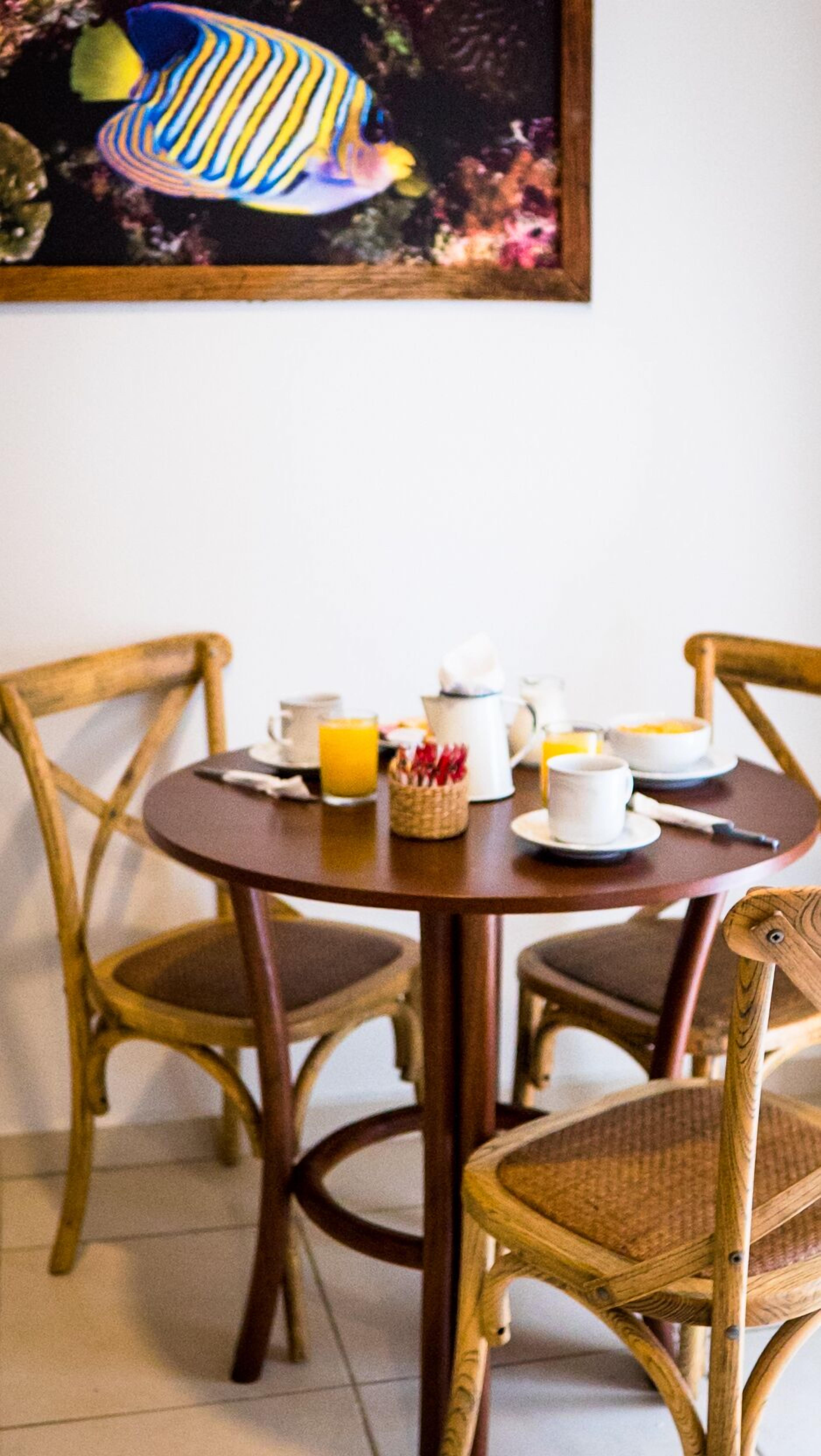 A dining table with chairs, a painting, and breakfast items.