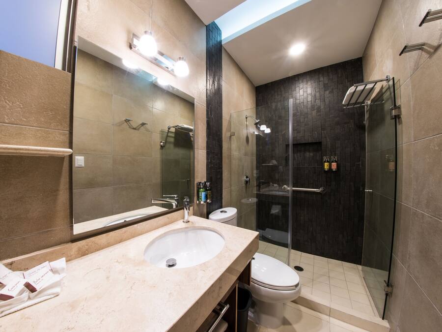 Uma casa de banho moderna com uma grande pia, espelho e cabine de duche em vidro.