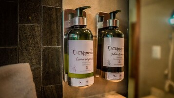 Dos botellas de crema corporal y jabón de manos del hotel Clipperton sobre una pared.