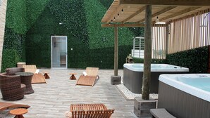 Un espace extérieur aménagé avec des sièges, un jacuzzi et une pergola en bois.