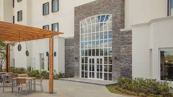 A modern building with a stone facade, large windows, and outdoor seating area.