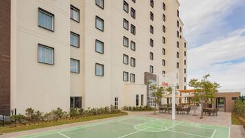 A multi-story hotel with a basketball court and outdoor seating area.