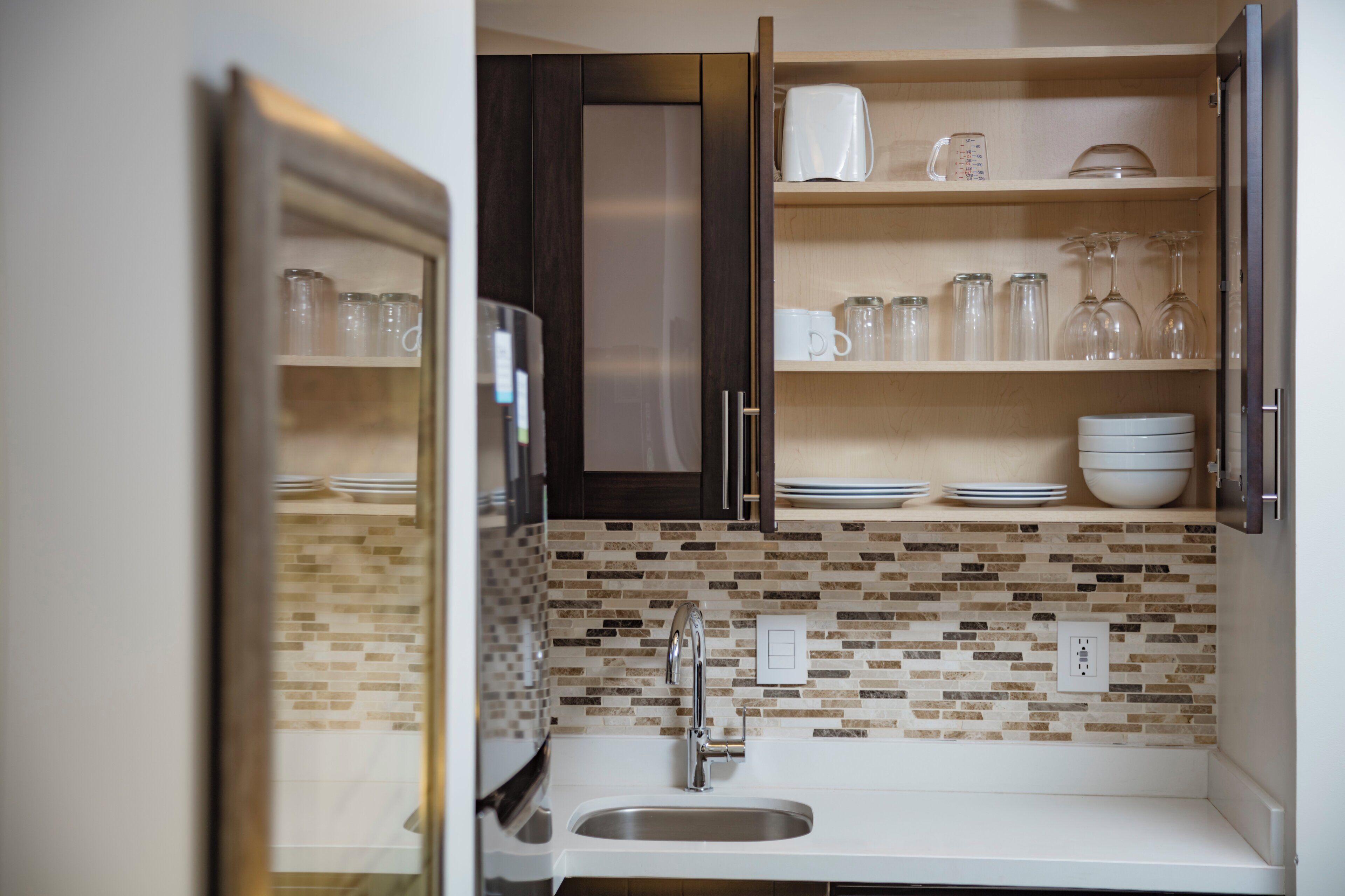 A modern kitchen with a built-in dishwasher, a stainless steel sink, and a tiled backsplash.