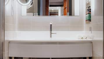 Un baño moderno con un espejo grande, un lavabo blanco y una ducha con mampara de vidrio.