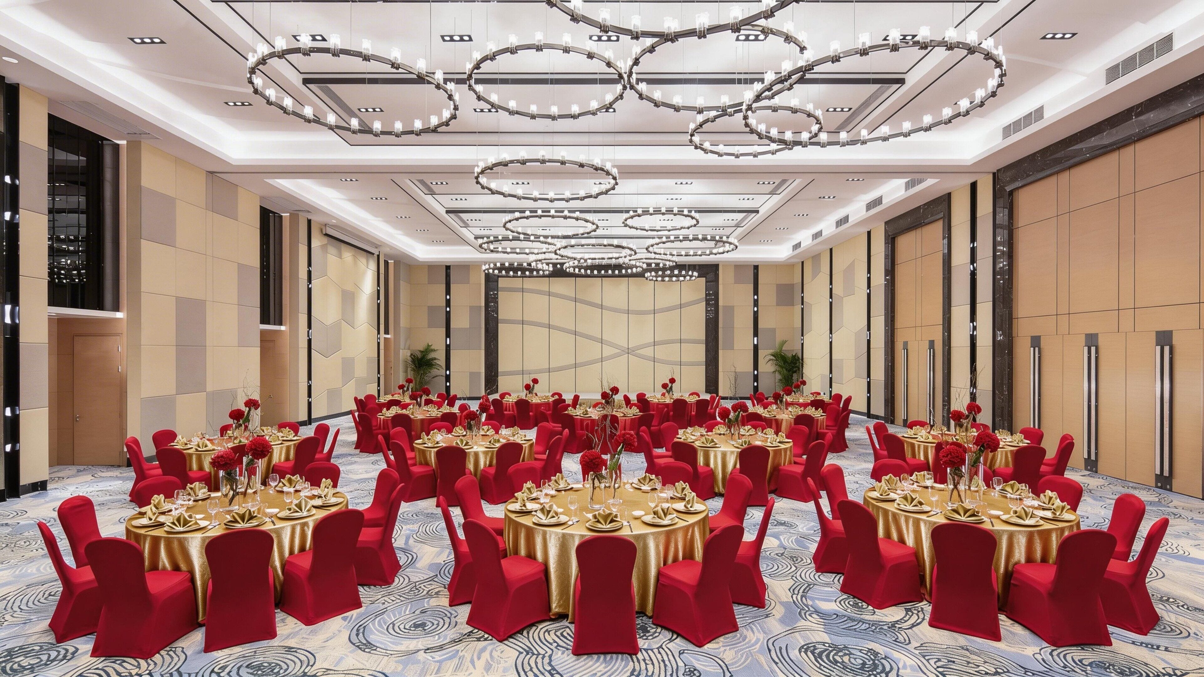 Un salón de conferencias con mesas redondas, sillas rojas y manteles dorados.