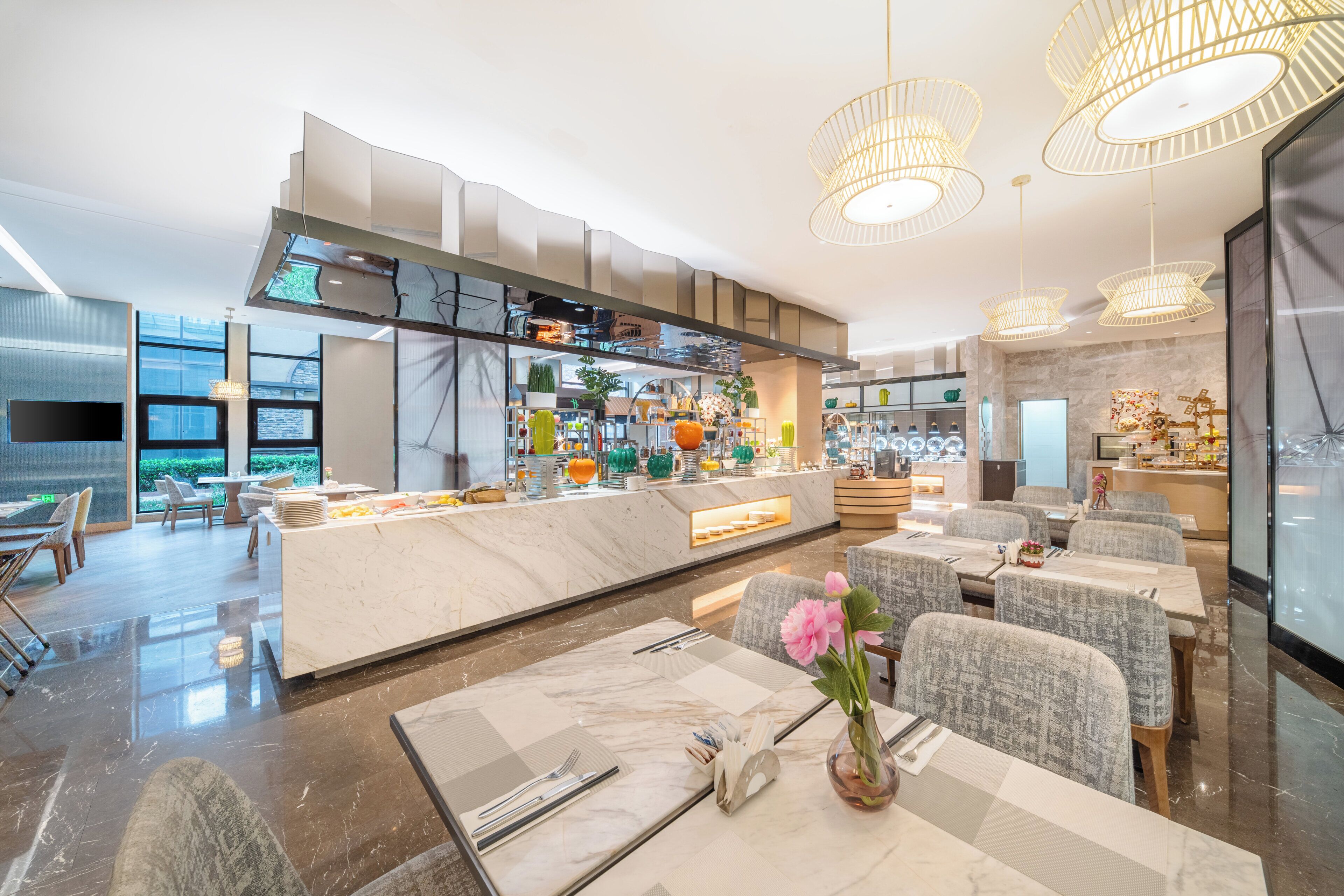 A modern restaurant with a marble bar, comfortable seating, and pendant lighting.