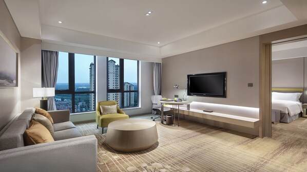 A modern hotel room with a large window, a flat-screen TV, a sofa, a desk, and a bed. - Holiday Inn Tianjin Wuqing (Tianjin)