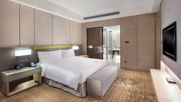 A modern hotel room with a bed, bedside table, lamp, and a TV.