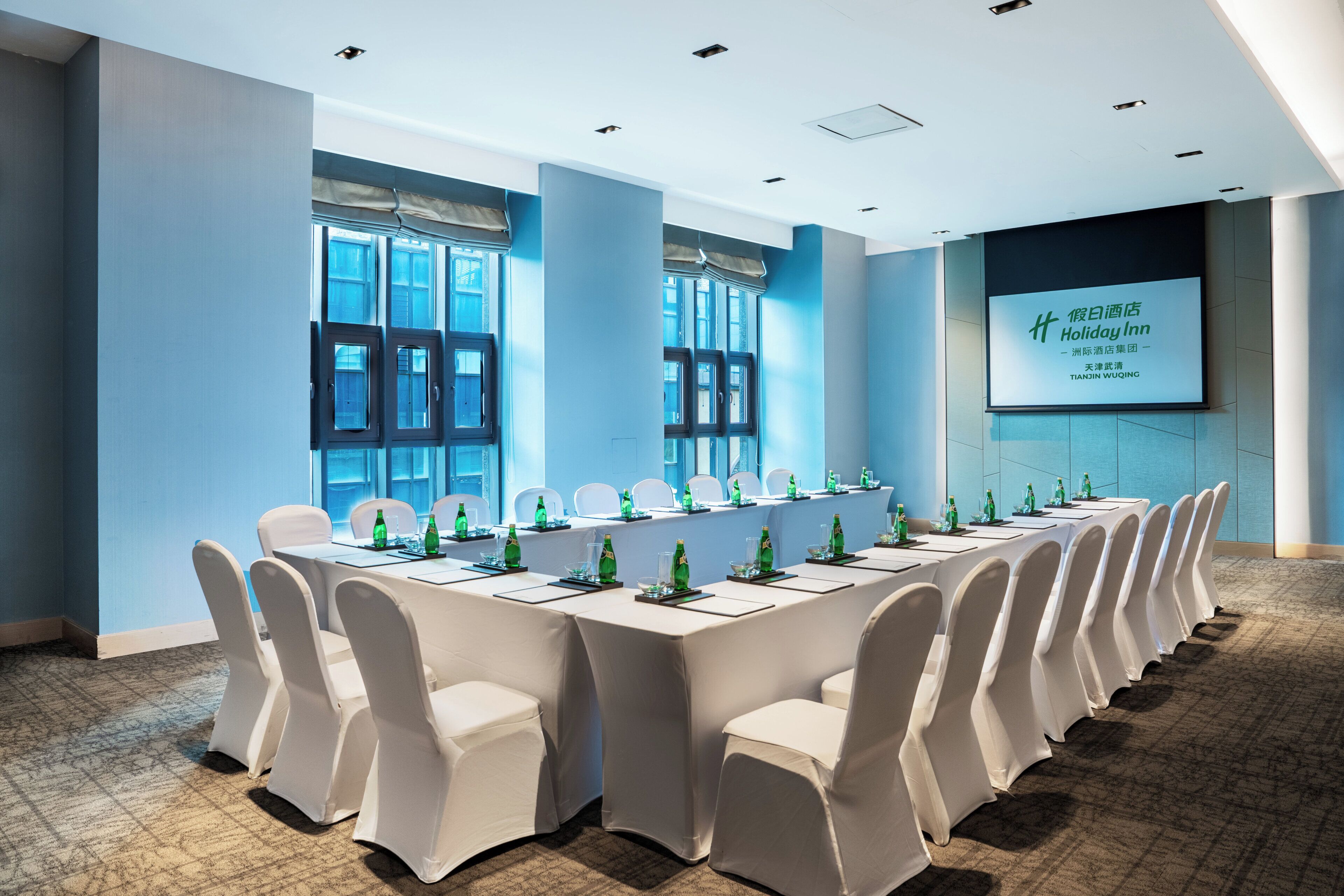 A conference room with a long table, chairs, and a projection screen displaying text.