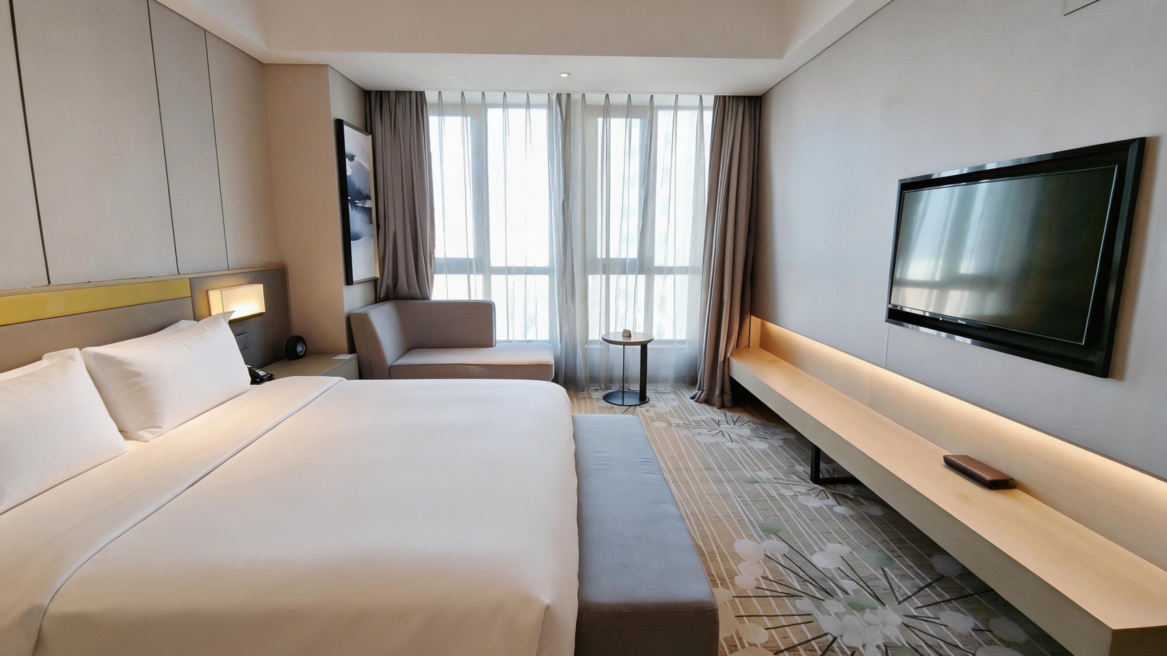 Una habitación de hotel con una cama grande, un sofá, un televisor y una mesita.