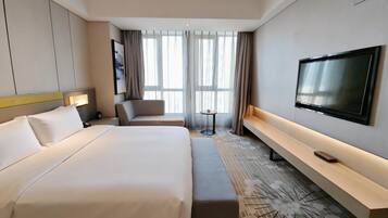 Una habitación de hotel con una cama grande, un sofá, un televisor y una mesita.