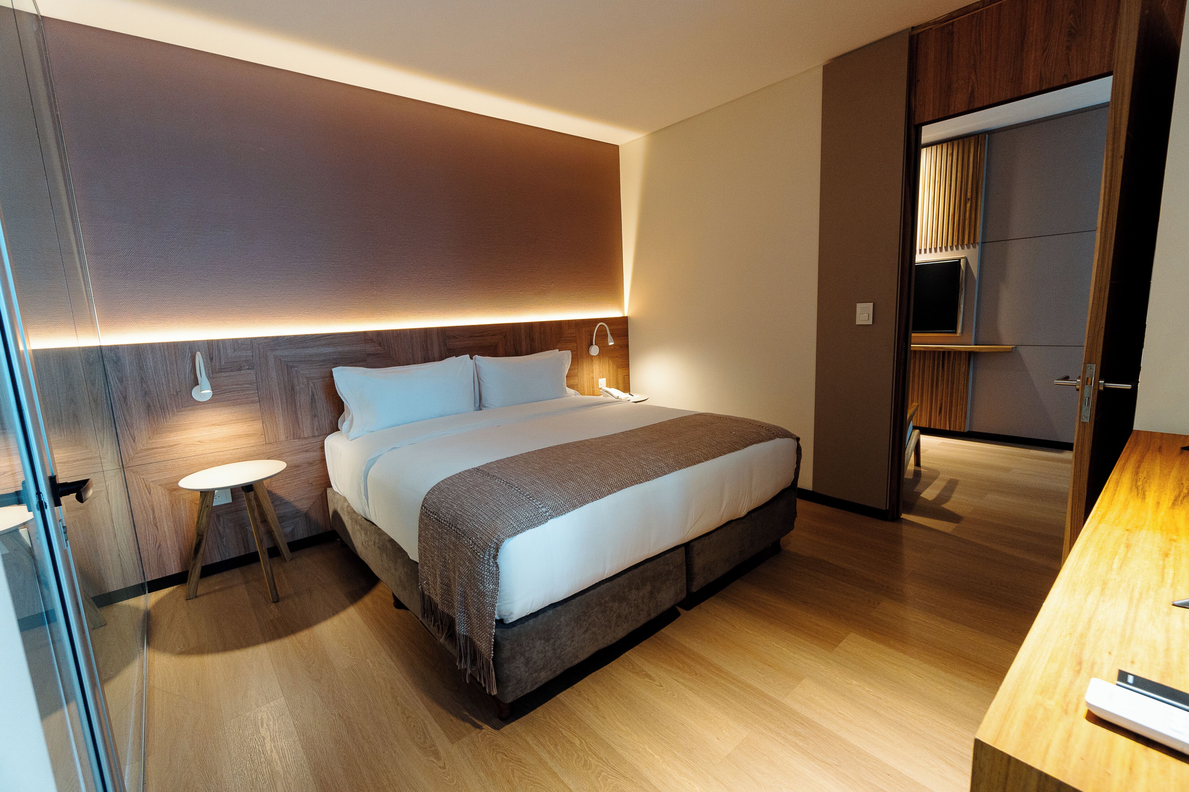A modern bedroom with a bed, bedside tables, and a wardrobe.