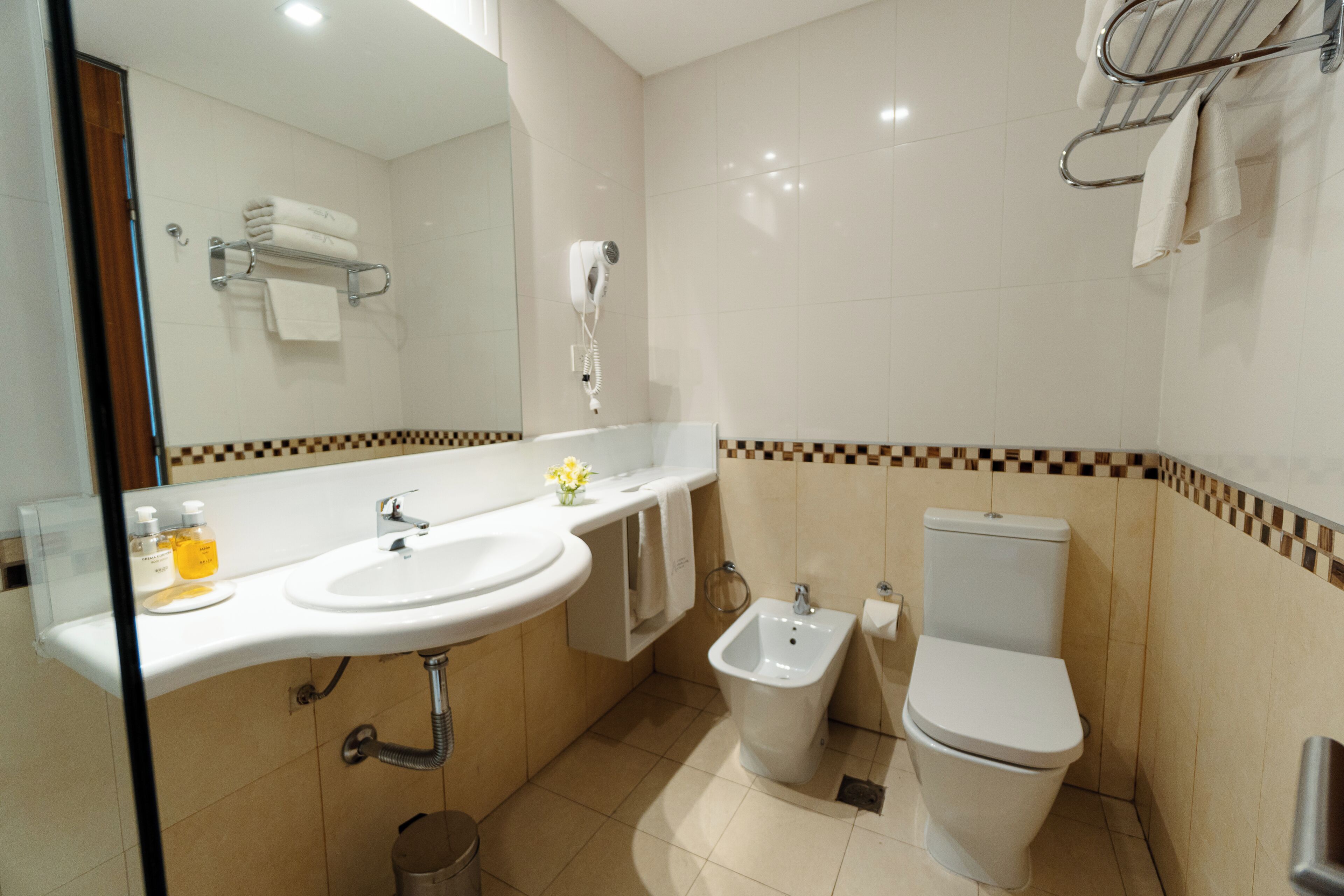 A bathroom with a sink, bidet, toilet, and a towel rack.
