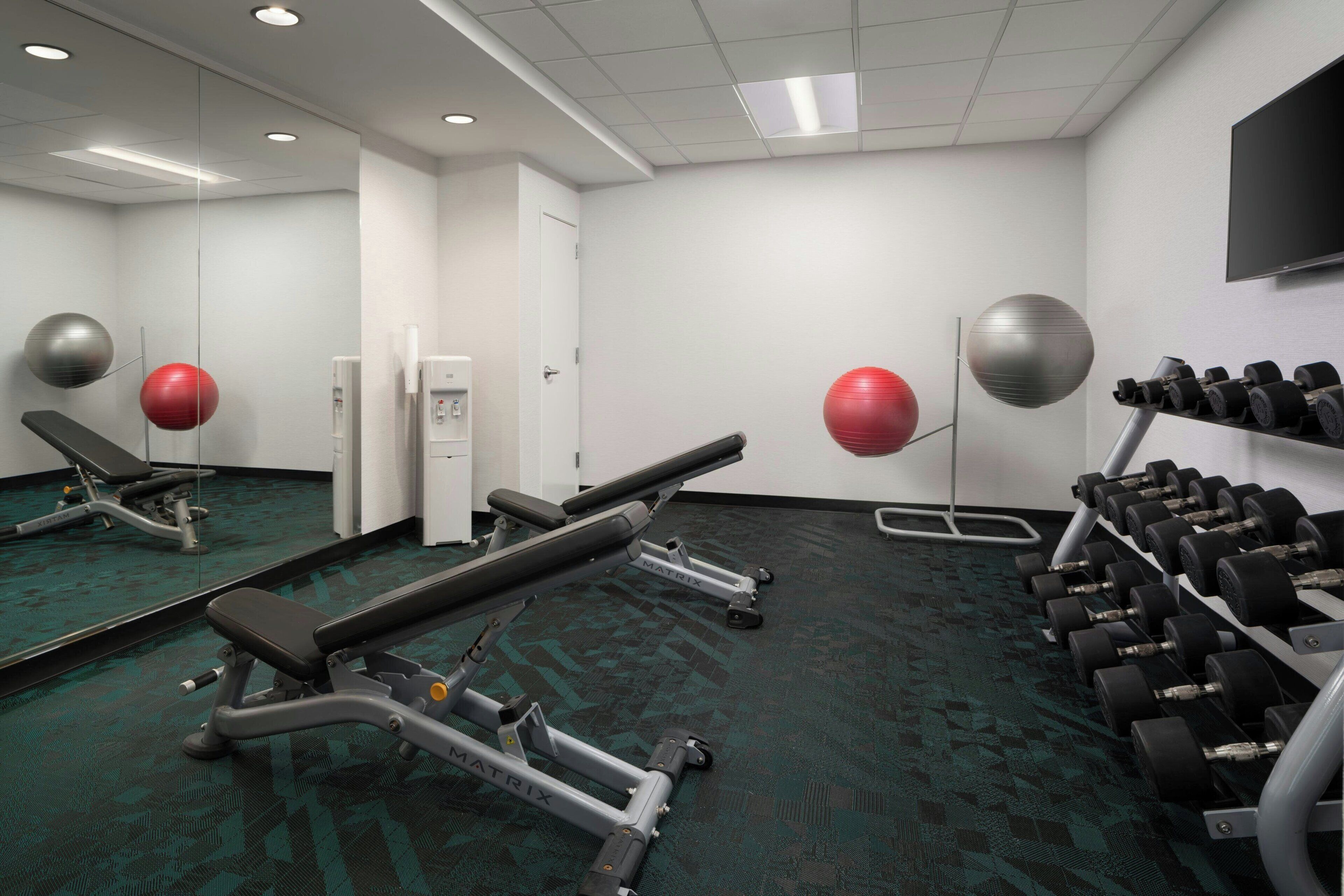 Une salle de sport équipée de matériel d’exercice, notamment un banc, des haltères et des ballons d’exercice.