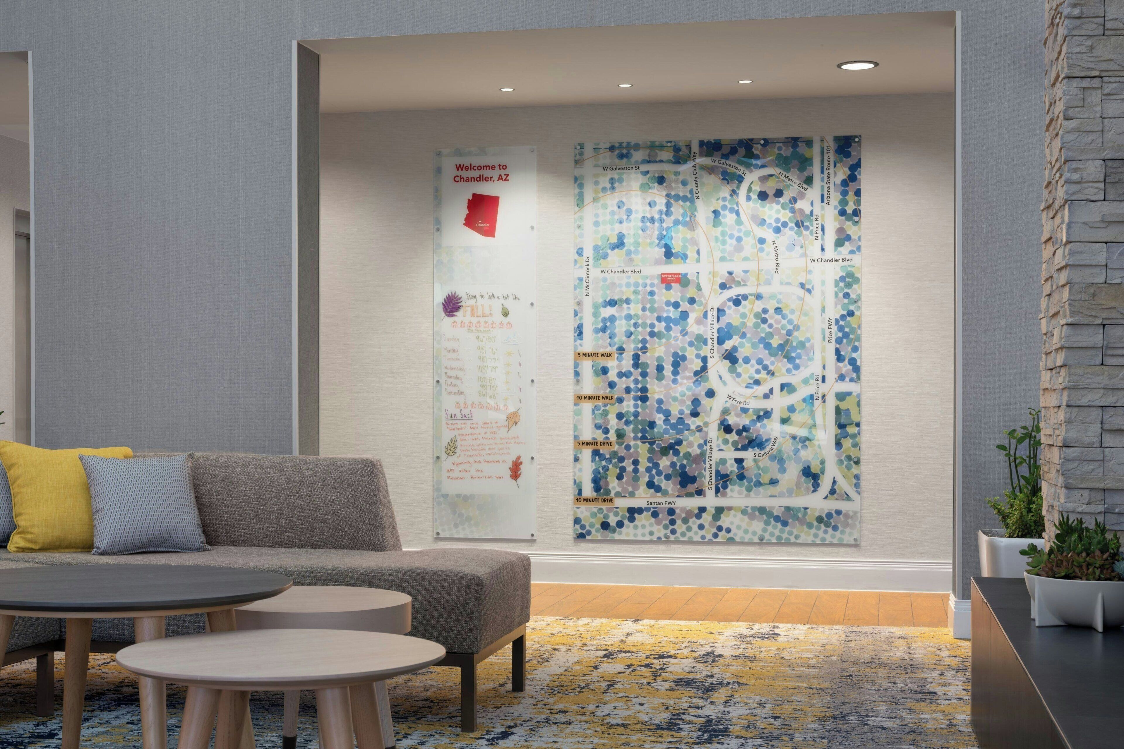 A modern lobby with a grey sofa, round tables, a map mural, and a stone accent wall.