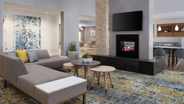 Una sala de estar moderna con un sofá modular, una chimenea, un televisor de pantalla plana y un comedor con mesa y sillas.